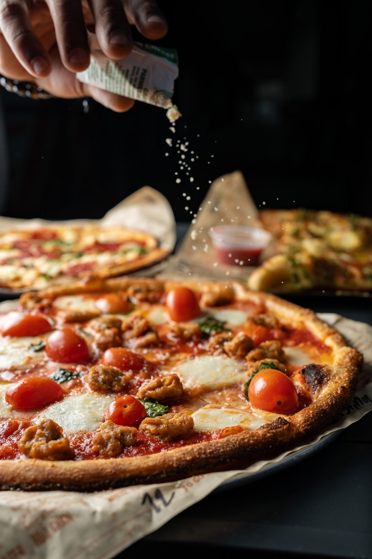 A hand sprinkling seasoning over a dish as a finishing touch