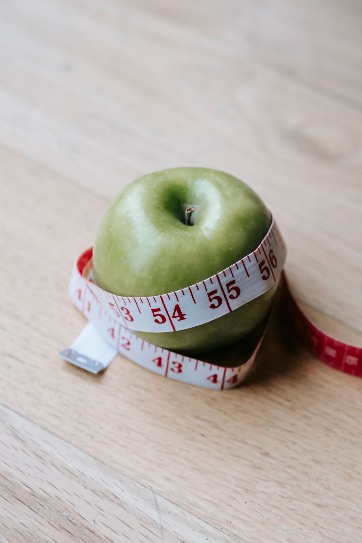 Green apple wrapped with a measuring tape — measuring how much
